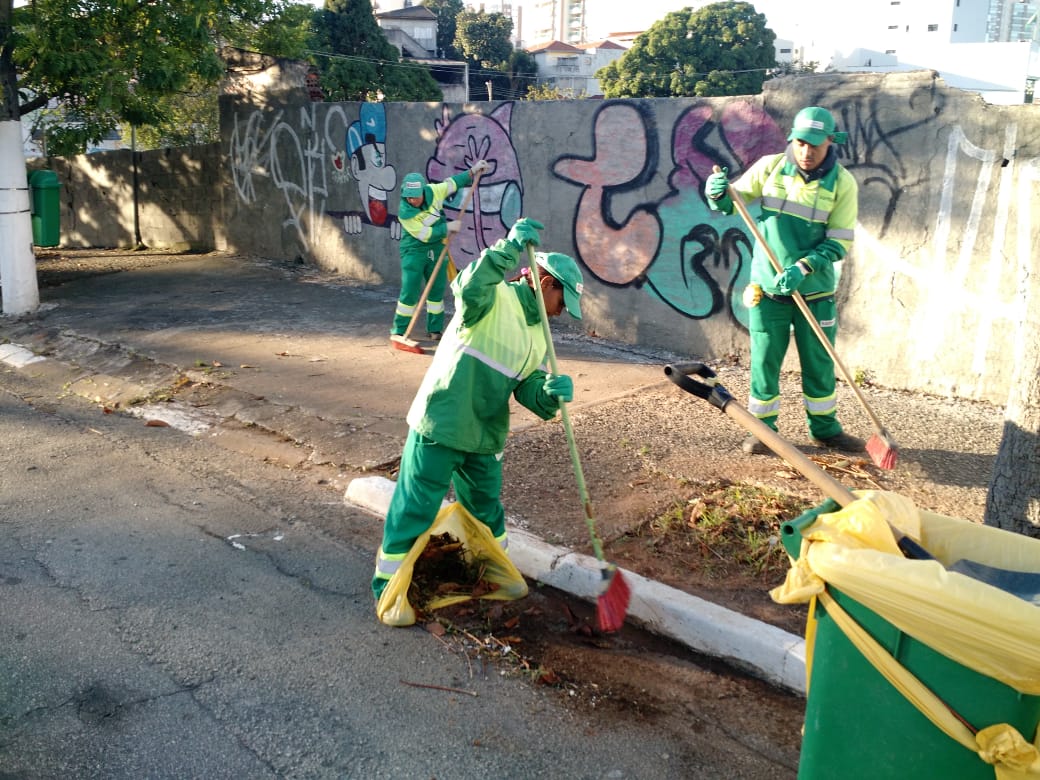 Pessoas varrendo a guia da rua